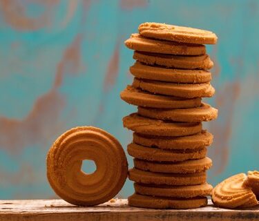 Stack of butter cookies/biscuits on wooden board with teal green rustic background